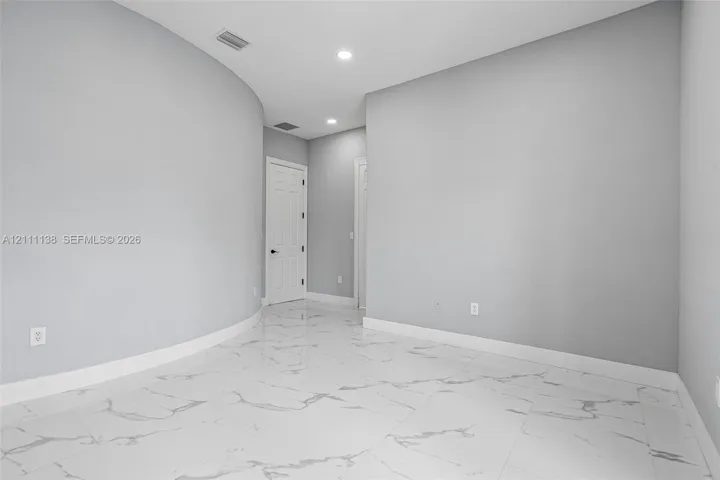 Interior space featuring polished large-format tile flooring with veining, curved wall architecture, and recessed ceiling lighting