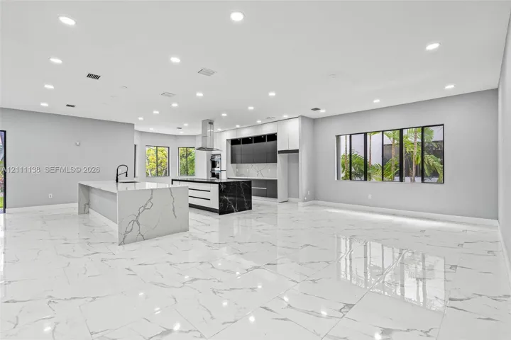 Open-concept kitchen featuring dual islands with veined stone-finish countertops, matte black plumbing fixtures, two-tone flat-panel cabinetry, and polished large-format tile flooring