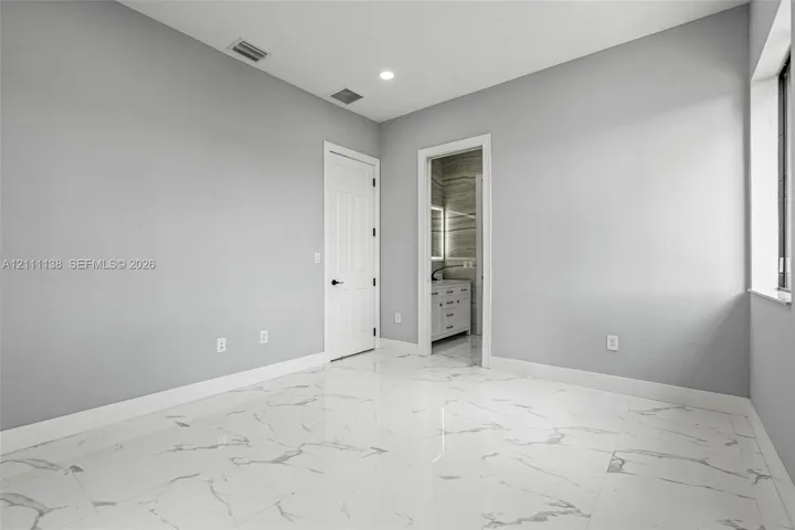 Polished stone-finish flooring with large-format veining, recessed lighting, and a multi-panel door