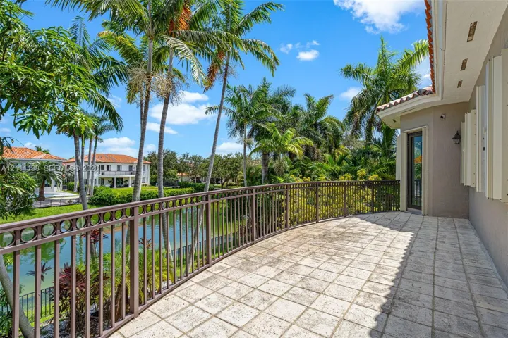 Covered balcony featuring stone tile flooring, decorative metal railing, and direct water frontage
