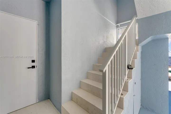 Interior staircase featuring stone-finish treads, a vertical bar metal railing, and a minimalist door with matte black hardware