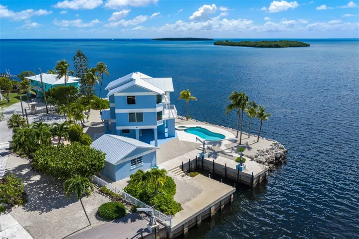 Waterfront residence featuring a metal roof, private swimming pool, concrete dock, and multi-level structure