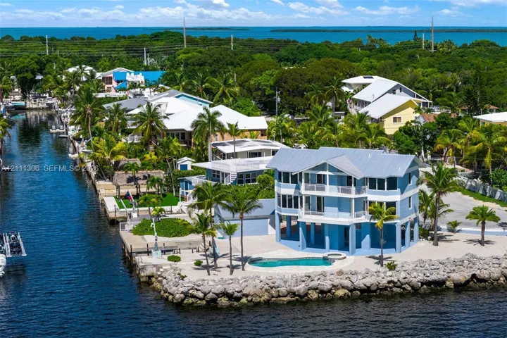 Waterfront residence featuring a metal roof, stacked porches, private swimming pool with integrated spa, and direct canal access