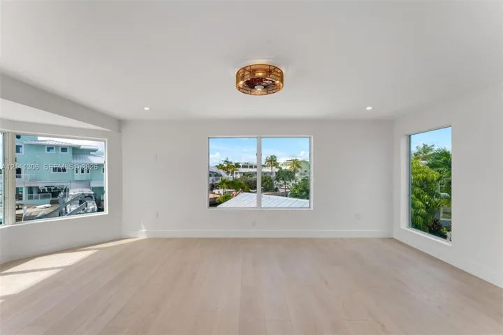Light-filled room featuring wood-finish flooring, recessed lighting, and a circular wicker-style ceiling fixture