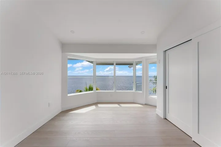 Bay window with expansive water scenery, recessed lighting, wood-finish flooring, and sliding door access to a balcony