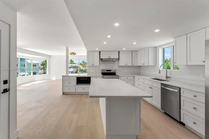 Kitchen featuring white Shaker cabinetry, quartz countertops, a central island, recessed lighting, and wood-finish flooring