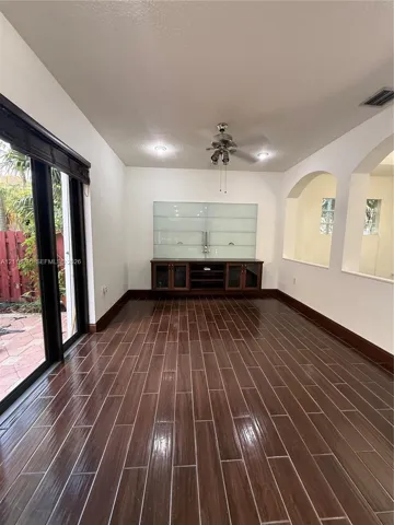 Wood-finish flooring, built-in cabinetry with glass shelving, recessed lighting, ceiling fan, and sliding glass doors