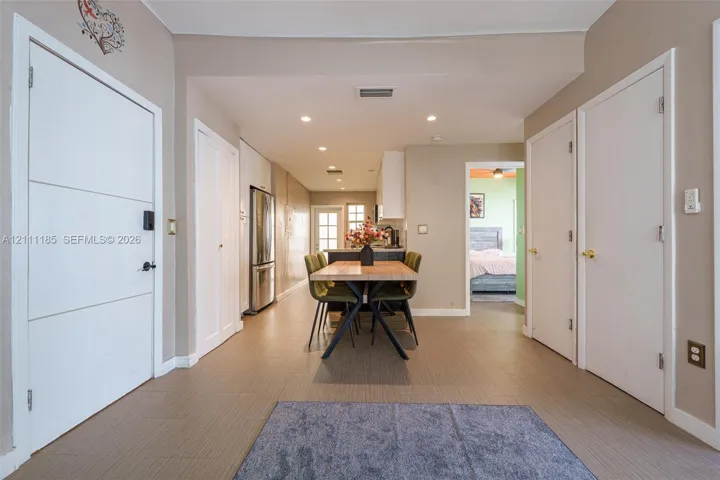 Neutral-toned interior featuring recessed lighting, tile flooring, and multiple solid-core interior doors with metallic hardware