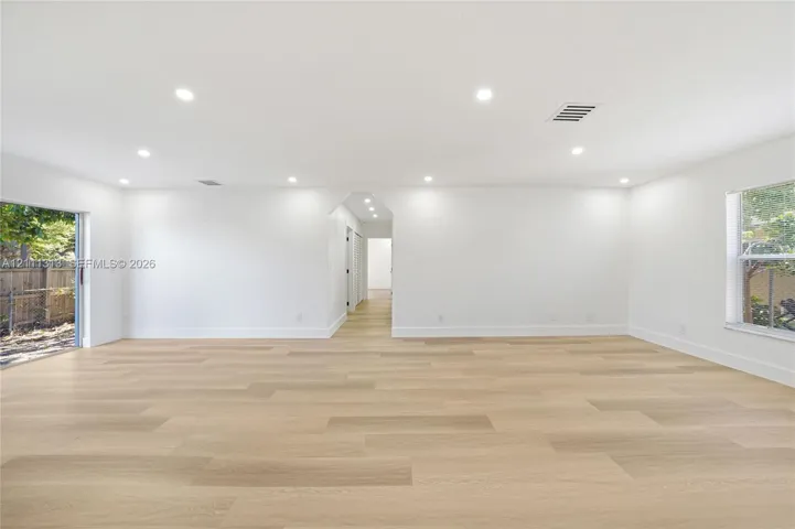 Open interior space featuring light wood-finish flooring, recessed lighting, and a glass sliding door