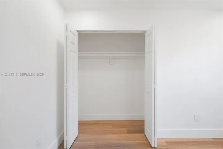 Closet featuring white bi-fold doors, built-in shelving, and wood-finish flooring