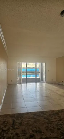Interior space featuring large-format neutral tile flooring and sliding glass doors leading to an exterior balcony