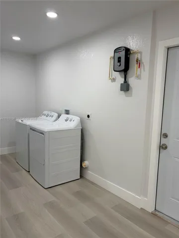 Laundry area featuring wood-finish flooring, recessed lighting, and a wall-mounted tankless water heater