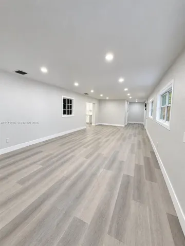 Open interior space featuring wood-finish flooring, recessed lighting, and multi-pane windows with crisp white trim