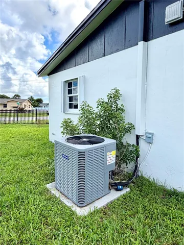 Exterior profile featuring a white stucco facade, dark-toned vertical siding, a single-hung window with shutters, and an external HVAC condenser unit on a concrete pad