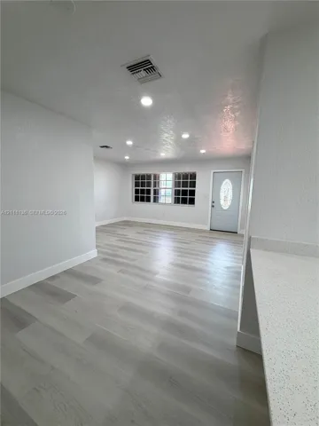 Interior space featuring wood-finish flooring, recessed lighting, neutral wall paint, multi-pane window, and an exterior door with an oval glass insert