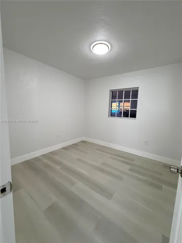 Interior room featuring wood-finish flooring, a multi-pane window, and a flush-mount ceiling light fixture
