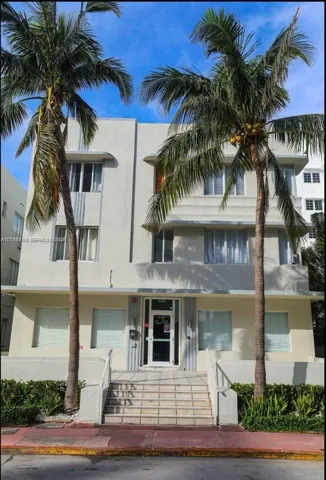 Art Deco exterior featuring a symmetrical facade, concrete-framed windows, vertical decorative fluting, and elevated stone entry stairs