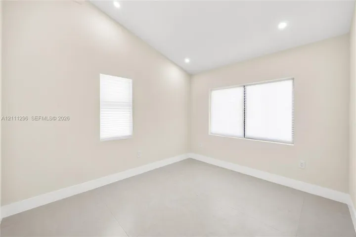 Vaulted ceilings featuring recessed lighting, large-format neutral tile flooring, and multiple windows with integrated blinds