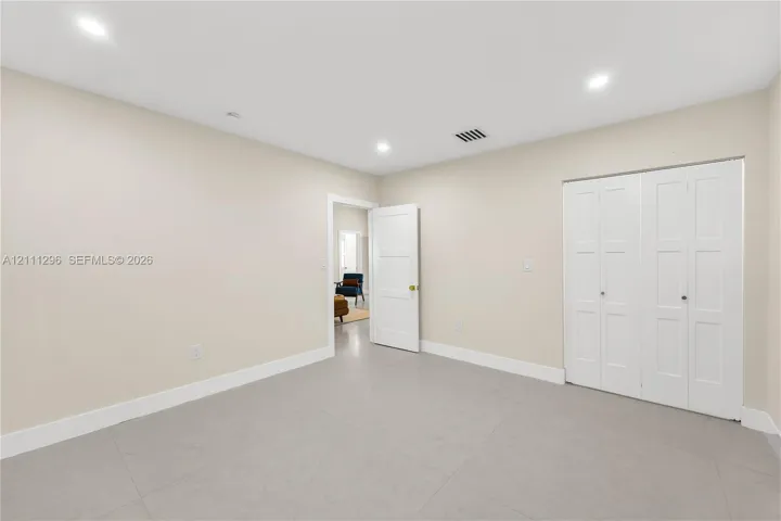 Neutral-toned room featuring recessed lighting, smooth-finish flooring, and a multi-panel door closet with white finish