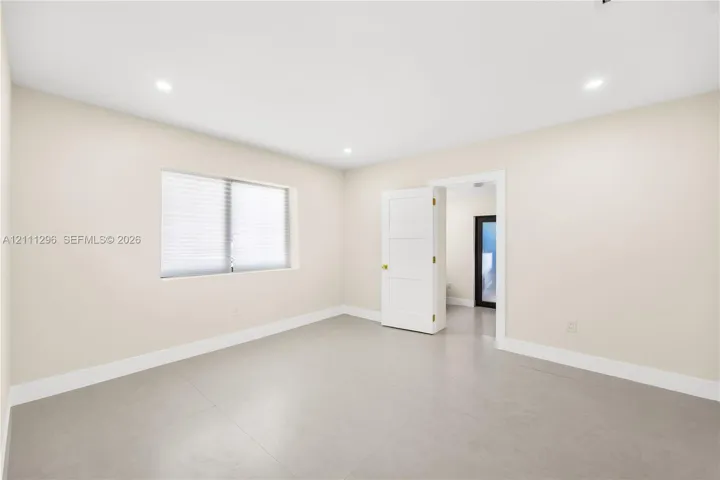 Neutral-toned tile flooring, recessed ceiling lighting, and a three-panel interior door