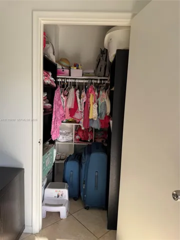 Reach-in closet featuring white wire shelving, a multi-cube storage organizer, and diagonal tile flooring