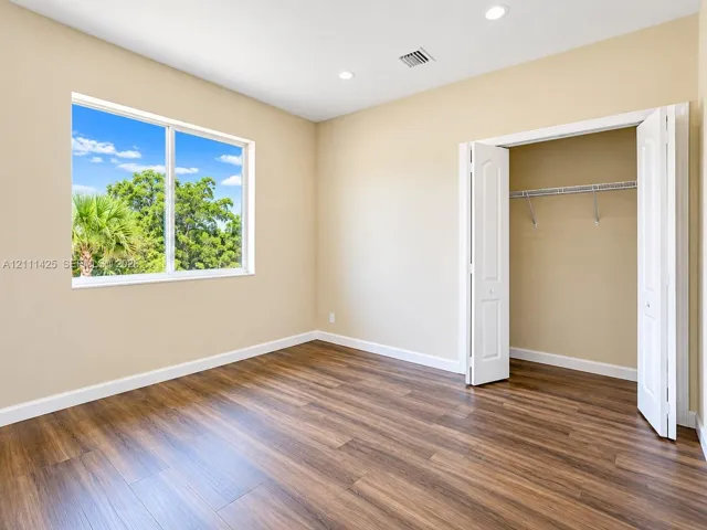 Interior room featuring wood-finish flooring, recessed lighting, a large picture window, and a reach-in closet with double bifold doors