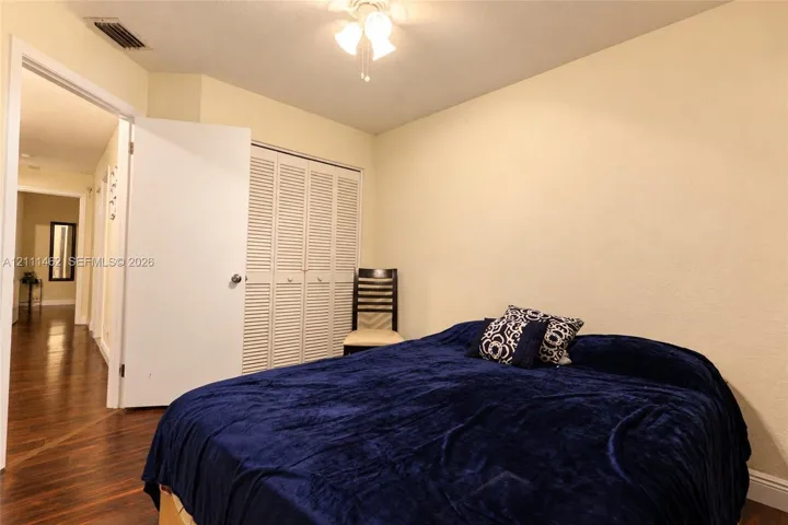 Room featuring wood-finish flooring, ceiling-mounted light fixture, and built-in closet with louvered doors