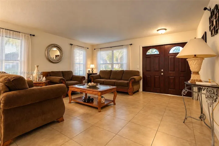 Spacious room featuring tile flooring, double entry doors with glass inserts, and multiple large windows