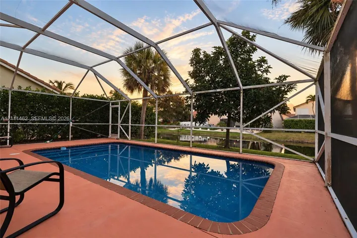 Screened-in pool enclosure with a brick-paver border and concrete deck