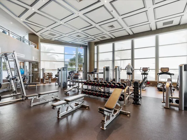 Fitness center featuring a coffered ceiling, floor-to-ceiling windows, and impact-resistant rubber flooring