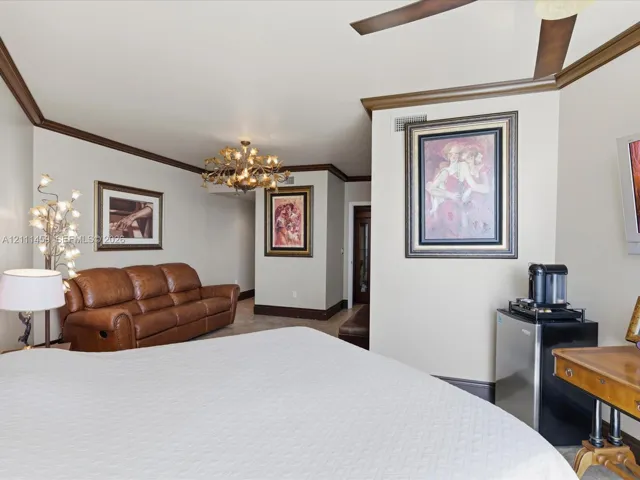 Vaulted ceilings with crown molding, decorative chandelier, and ceiling fan