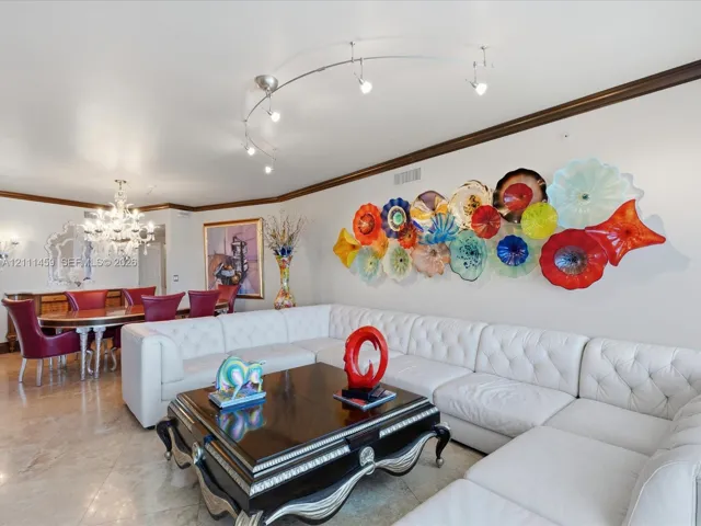 Polished stone flooring, crystal chandelier, curved track lighting, and decorative crown molding