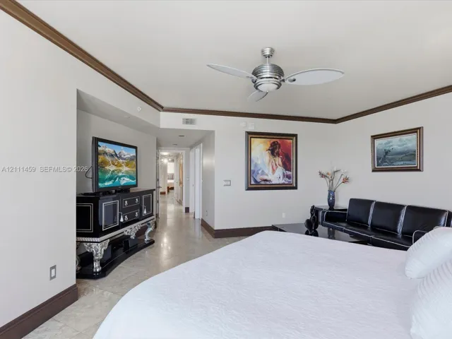 Neutral wall paint, crown molding, stone flooring, and a modern metal ceiling fan with integrated lighting