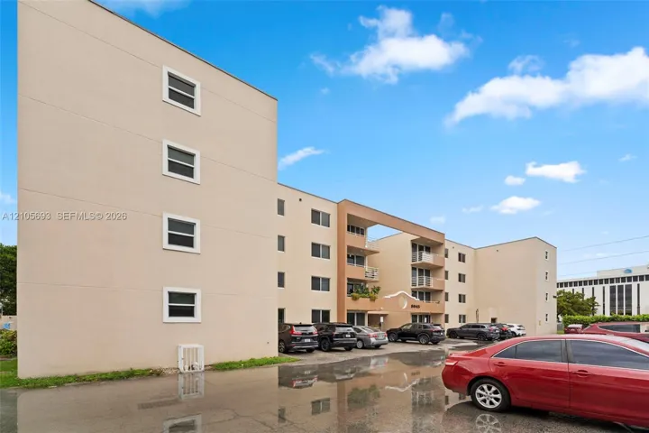 Multi-story exterior featuring a smooth stucco facade, inset balconies, and integrated paved parking