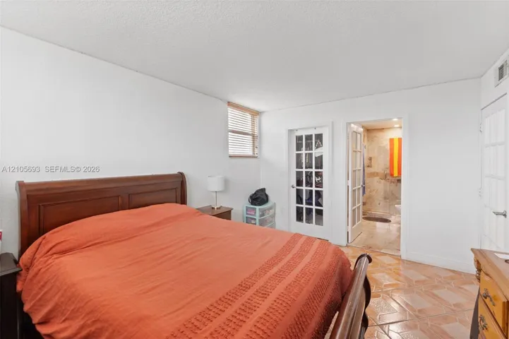 Room featuring ceramic tile flooring, horizontal blinds, and two sets of white French doors