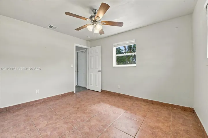 Interior room featuring oversized ceramic tile flooring, a multi-blade ceiling fan with integrated light fixture, a six-panel door, and a single-hung window