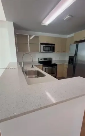 Kitchen featuring stone-finish countertops, stainless steel appliances, flat-panel cabinetry, a stainless steel undermount sink, and a high-arch pull-down faucet