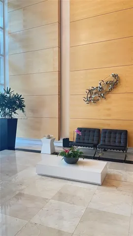 Floor-to-ceiling light-toned wood paneling, expansive light-toned stone tile flooring, and integrated metal wall art
