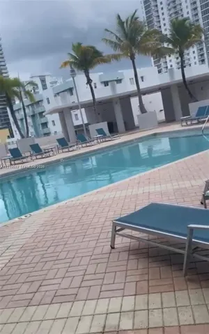Swimming pool with brick paver decking and palm trees
