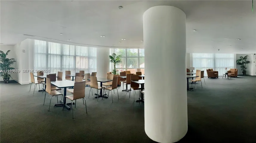 Expansive open-concept room featuring floor-to-ceiling windows, recessed lighting, and a prominent cylindrical architectural column