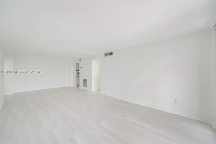 Expansive living area featuring light-toned wood-finish flooring and neutral-toned wall finishes