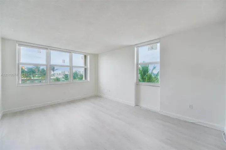 Interior space featuring light wood-finish flooring, neutral wall tones, and multiple large windows