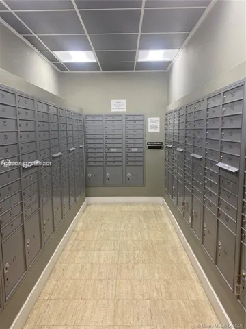 Mail center featuring wall-mounted metal mailboxes, grid-patterned drop ceiling, and neutral tile flooring