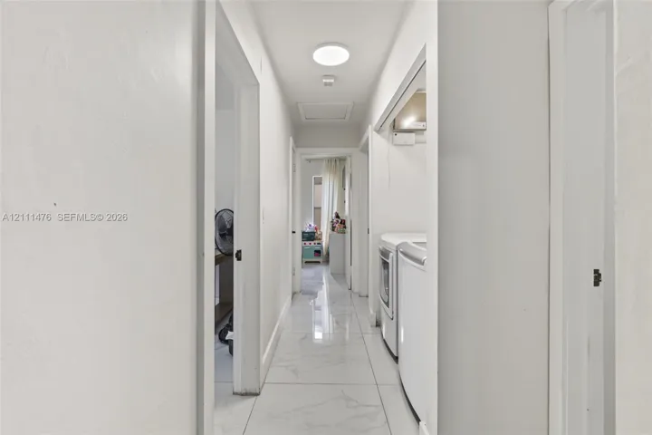 Interior hallway featuring large-format stone-look tile flooring and a flush-mount circular ceiling light