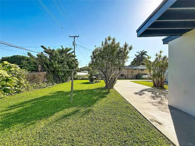 Spacious backyard featuring a level lawn, concrete patio, and mature landscaping