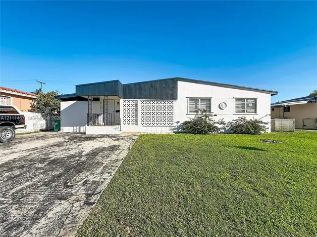 Mid-century modern exterior featuring a low-slope roofline, decorative breeze block screening, contrasting dark trim, and a concrete driveway