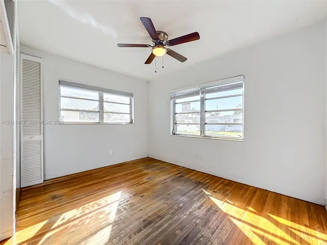 Wood-finish flooring, multi-pane windows, ceiling fan with integrated lighting, and louvered-door closet