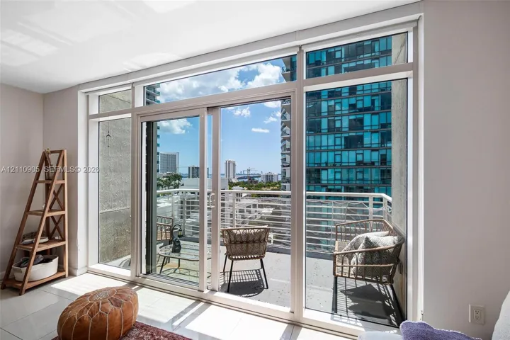 Floor-to-ceiling glass sliding doors with white frames, tile flooring, and a private balcony featuring metal railings