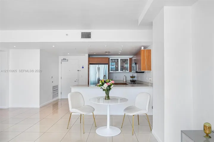 Kitchen featuring flat-panel wood-finish cabinetry, stainless steel appliances, and a solid-surface breakfast bar with recessed lighting throughout