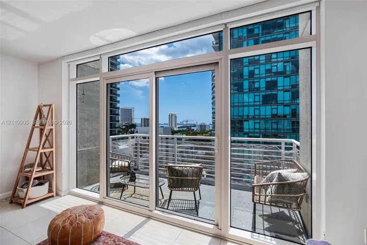 Floor-to-ceiling windows, sliding glass door, and private balcony featuring horizontal metal railings